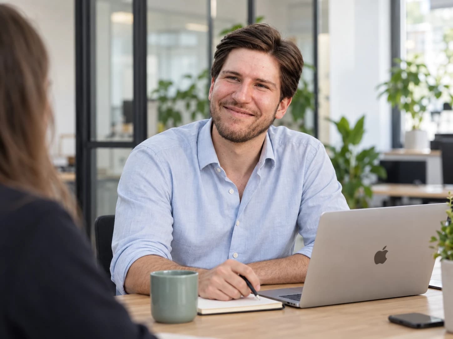 Jonathan Glasow im Gespräch mit einer Kollegin am Schreibtisch im hellen Büro